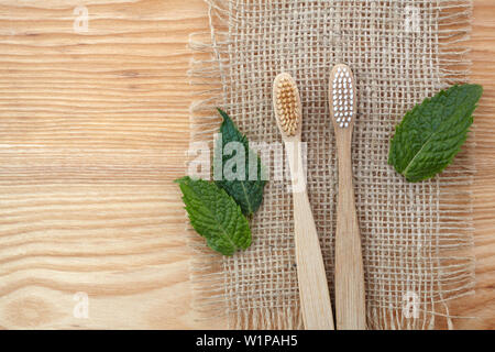Null Abfall Konzept. Bambus Zahnbürste auf Holz- Hintergrund mit grüner Minze Blatt. Kunststoff kostenlose Essentials Stockfoto