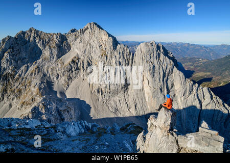 Mann sitzt auf Rock spire und Blick auf die Felswände des vorderen und hinteren Karlspitze, von der Hinteren Goinger Halt, Wilder Kaiser, Kaiser, Ty Stockfoto