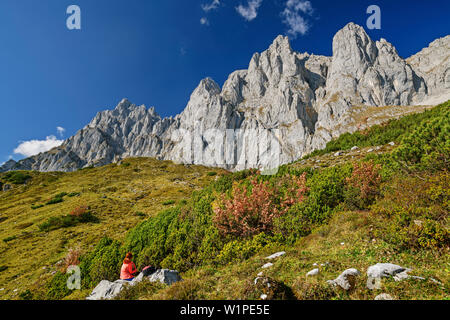 Frau wandern sitzt auf Felsen und mit Blick auf die Felswände der Kaiser, Wilder Kaiser, Kaiser, Tirol, Österreich Stockfoto
