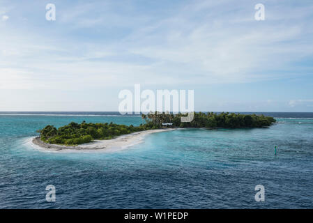 Eine lange und schmale Insel mit Palmen und Büschen bedeckt und mit einem schmalen Streifen von weißem Sand steht in türkisfarbenem Wasser unter einem leicht cloude Stockfoto