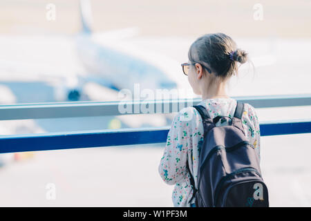 Ein kleines Mädchen warten auf der Aussichtsplattform am Flughafen - eine unscharfe Silhouette der Flugzeug im Hintergrund sichtbar durch das Fenster Stockfoto