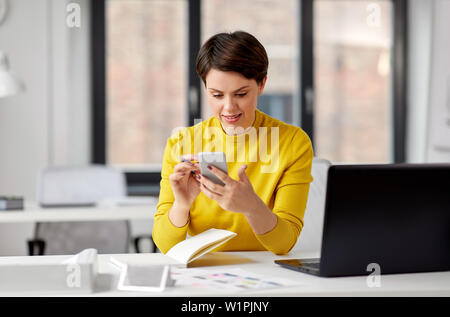 Lächelnd UI-Designer über Smartphone im Büro Stockfoto