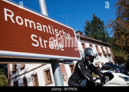 Motorradfahrer hinter dem Schild für Romantische Straße romantische Straße durch Unteres Taubertal, Bronnbach, in der Nähe von Wertheim, Spessart-Mainland, Franco Stockfoto
