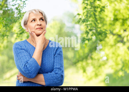 Ältere Frau denken über die natürlichen Hintergrund Stockfoto