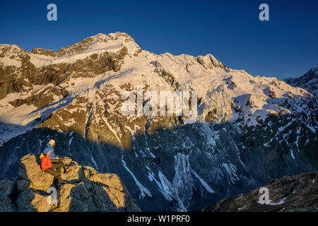 Der Mann und die Frau sitzt auf Felsen und Blick auf Mount Sefton und Hocker, von Mueller Hut, Hooker Valley, Mount Cook Nationalpark, UNESCO Welter Stockfoto