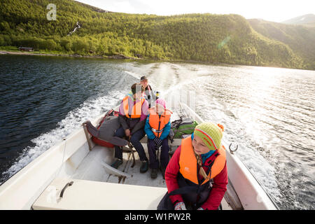 Zwei Mädchen, eine Frau und ein Mann in einem Boot. Mit dem Wassertaxi auf See Teusajaure von Hütte ward Loland Lindholm. Trekking auf dem Kungsleden, Laponia, Lappland, Stockfoto