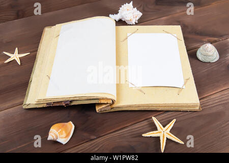 Vintage photo album auf Holzuntergrund mit Muscheln. Erinnerungen an den Rest des Meeres. Stockfoto