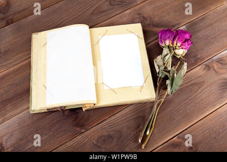 Vintage photo album auf Holzuntergrund mit trockenen Blüten. Erinnerungen an Urlaub. Stockfoto