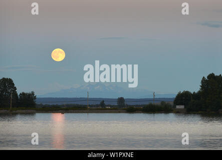 Vollmond über Cascade Range. Mondaufgang auf der Fraser River in Richmond, British Columbia, Kanada. Stockfoto