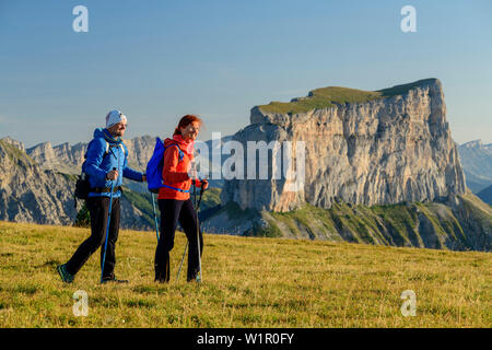 Ein Mann und eine Frau gehen auf Wiese mit Mont Aiguille im Hintergrund, von der Tête Chevalier, Vercors, Dauphine, Dauphine, Isère, Frankreich Stockfoto