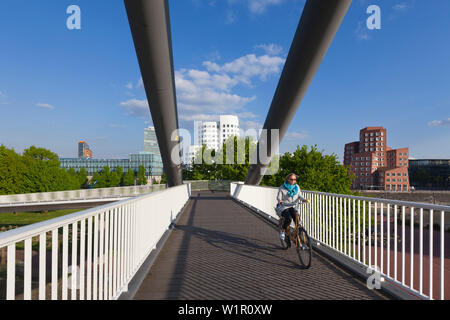 Radfahrer auf einer Brücke im Medienhafen, Blick auf die Neue Zollhof (Architekt: F.O. Gehry), Düsseldorf, Nordrhein-Westfalen, Deutschland Stockfoto