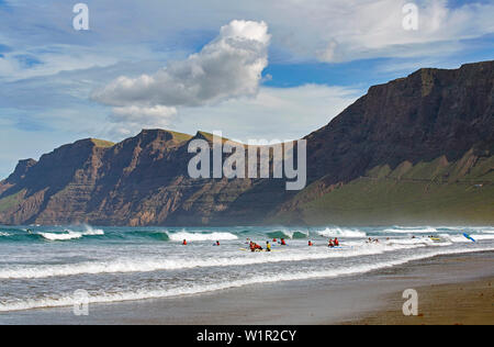 Famara Bucht am Fuße des Famara-gebirge, Surfer an der Playa de Famara, Atlantik, Lanzarote, Kanarische Inseln, Islas Canarias, Spanien, Europ. Stockfoto