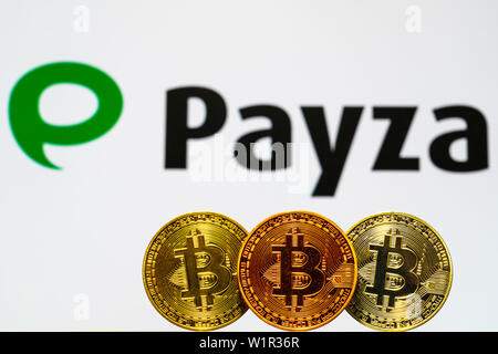 Gold Bitcoin Münzen mit der Payza Logo auf Hintergrund. Eine neue Art von Geschäft Finanzierung Konzept. Stockfoto