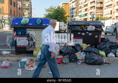 Rom, Italien, 27. Juni 2019: Mülltonnen voller Müll, unter den Straßen und Gebäuden der Stadt. Ein Bürger schaut sie ungläubig an. Stockfoto