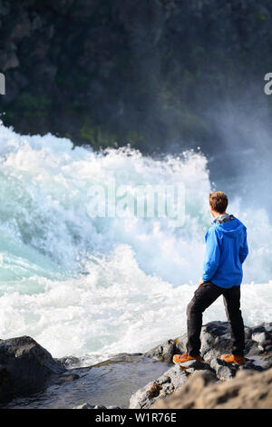 Island Tourist an dramatischen Fluss mit Wasserfall Godafoss. Mann Wanderer auf Reisen Besuchen touristischer Attraktionen und Wahrzeichen in der isländischen Natur auf Ring Road, Route 1. Stockfoto