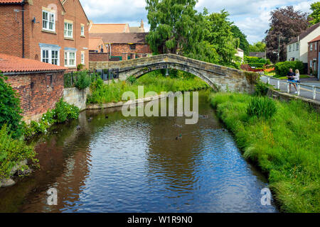 Mann und Frau im Chat von der 17C Pack Horse Brücke über den Fluß Leven im Stokesley North Yorkshire, auf dem alten Packesel Route von Durham, York Stockfoto