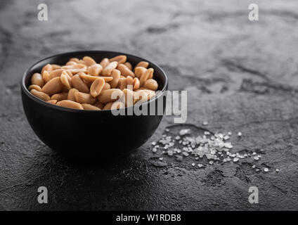 Gesalzen und geröstet Erdnüsse classic Snack in schwarz Schüssel auf Schwarzen Tisch. Stockfoto