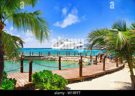 Blick vom Strand im Tropical Resort auf Kreuzfahrtschiffen angedockt am Port Stockfoto