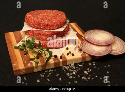 Rindfleisch Burger handgefertigte Prime Beef, auf einem Holzbrett auf schwarzem Hintergrund. Stockfoto
