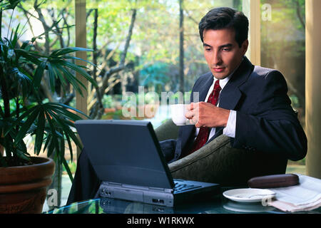 Unternehmer, die in einer Hotellobby trinken mit seinem Laptop Kaffee Stockfoto