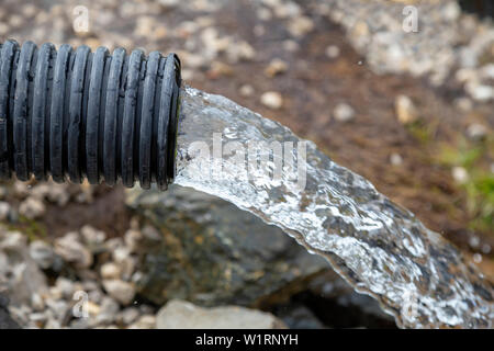 Strom von sauberem Wasser aus tiefen Brunnen ohne Strom. Kühl und frisch Natur Wasser Quelle aus dem Boden. Konzept: Ökologie und Gesundheit. Stockfoto