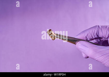 Die behandschuhte Hand mit Pinzette und bullet Gehäuse. Stockfoto