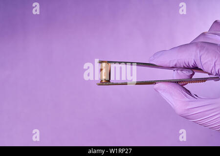 Die behandschuhte Hand mit Pinzette und bullet Gehäuse. Stockfoto