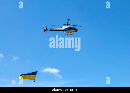 Der Helikopter fliegt mit dem nationalen Staat gelb Blaue Flagge der Ukraine. Ukrainische Flagge in den Himmel über der Stadt Dnjepr Dnjepropetrowsk. Die Ukraine Stockfoto