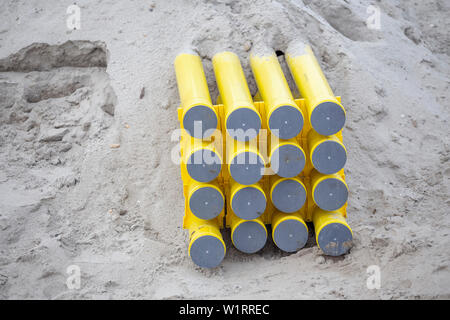 Gelb PVC-Rohre für Kabelsysteme im Sand vergraben. Pe-Rohre werden als Kanäle für optische Kabel (als Gehäuse für optisches Kabel, Anbietern verwendet Stockfoto