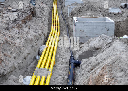 Gelb PVC-Pipeline für Kabelsysteme im Sand vergraben. Pe-Rohre werden als Kanäle für optische Kabel und zum Schutz tele verwendet Stockfoto