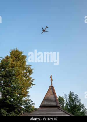 Landsitz von Gorki, Moskau, Russland - 20. Juni 2019: Orthodoxes Kreuz und Flugzeug. Orthodoxe Kirche aus Holz und ein Passagierflugzeug in den Himmel fliegen Stockfoto