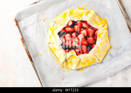 Hausgemachte Kuchen Erdbeere öffnen von gallet mit lila Basilikum und Balsamico Essig vor dem Backen auf einem Leichtmetall pan. Ansicht von oben Stockfoto