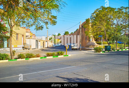 KASHAN, IRAN - 23. Oktober 2017: Die Straße der alten Stadt mit Linie der lebenden Gebäude, grün der öffentlichen Mellat Park und Ruinen von Adobe Festungsmauer Stockfoto