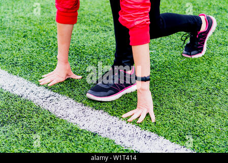 Ein Mädchen in schwarzen Gamaschen und einem rosafarbenen Blazer vorbereitet auf einem Laufband in eine Open-Air-Arena laufen zu lassen und steht in einem Runner darstellen. Stockfoto