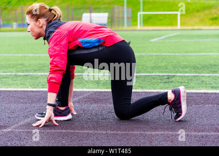 Ein Mädchen in schwarzen Gamaschen und einem rosafarbenen Blazer vorbereitet auf einem Laufband in eine Open-Air-Arena laufen zu lassen und steht in einem Runner darstellen. Stockfoto