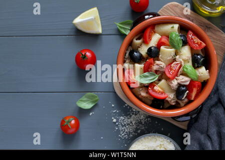 Pasta mit Thunfisch, Tomaten, schwarze Oliven und Parmesan auf dunklem Hintergrund. Ansicht von oben mit der Kopie. Stockfoto