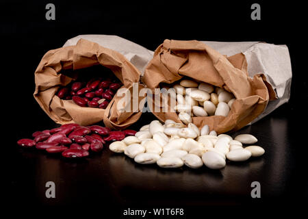 Bean in Papiertüten auf dem Küchentisch. Lebensmittelzutaten, die in der Küche verwendet. Der dunkle Hintergrund. Stockfoto