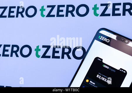 TZero Logos auf die Broschüre und das Smartphone mit dem tZERO Crypto App Screenshot. Stockfoto