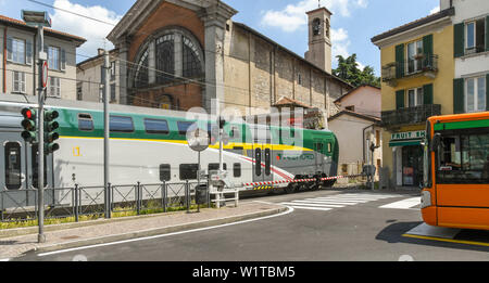 COMO, ITALIEN - JUNI 2019: Moderne elektrische Zug passiert über eine Straße überqueren, wie es fährt von der Stadt Como am Comer See. Ein Bus ist in der Stockfoto