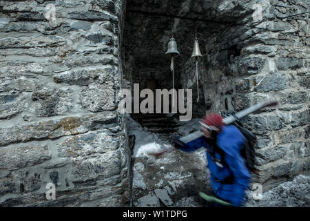 Skifahrerin wandern vorbei an kleinen Glocken einer Ruine, Gudauri, Mtskheta-Mtianeti, Georgien Stockfoto