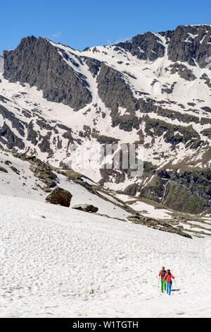 Mann und Frau wandern absteigend durch den Schnee zur Hütte Zuflucht Viso, Giro di Monte Viso, Monte Viso, Monviso, Cottischen Alpen, Frankreich Stockfoto