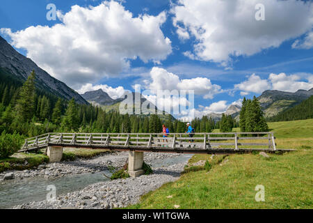 Ein Mann und eine Frau gehen auf der Brücke über den Lech, Lech Quelle lechweg, Berge, Vorarlberg, Österreich Stockfoto