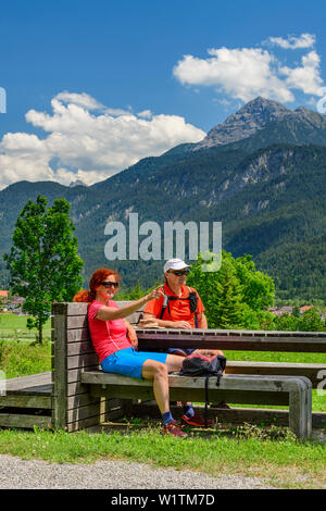 Der Mann und die Frau sitzt auf der Bank und mit einer Unterbrechung, Lechtaler Alpen im Hintergrund, Weißenbach, Lechweg, Tal von Lech, Tirol, Österreich Stockfoto