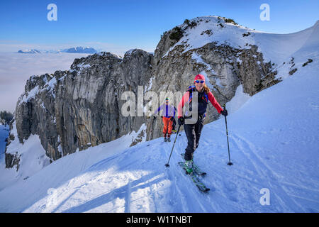 Drei Personen backcountry Skiing aufsteigend unter Felswand in Richtung Hintere Sonnwendjoch, Hintere Sonnwendjoch, Bayerische Alpen, Tirol, Österreich Stockfoto