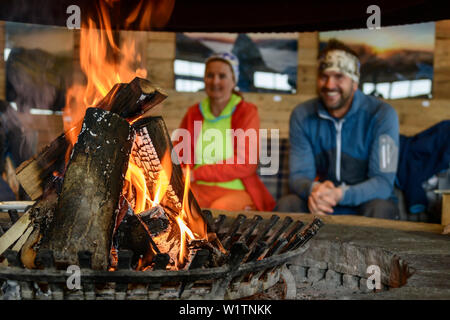 Brennenden Holzscheite im offenen Feuer, Mann und Frau, im Hintergrund, Ski Arena Kaltenbach, Tal der Zillertaler und Tuxer Alpen, Tirol, Österreich Stockfoto