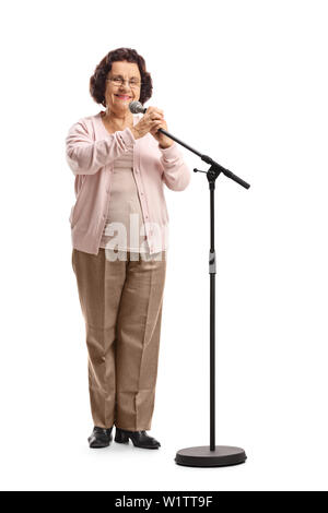 Volle Länge Portrait von einer alten Frau vor ein Mikrofon auf einem Stativ auf weißem Hintergrund Stockfoto