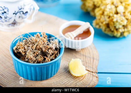 Getrocknete Lindenblüten in Schale mit Honig und Zitrone auf Holz- Hintergrund Stockfoto