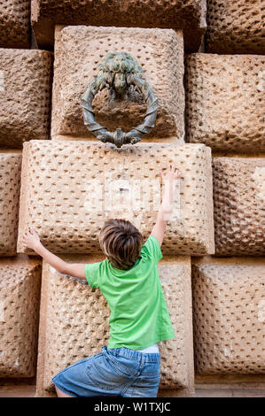 Kind, das versucht den Messingring, Alhambra, Granada, Andalusien, Spanien, Europa zu erreichen. Stockfoto