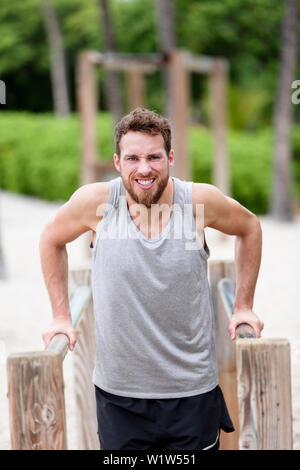 Mann schwer tun Krafttraining Übungen - Fitness Cardio Workout. Junge kaukasier männlichen Athleten arbeiten Sie hart auf outdoor Jungle Gym/Monkey Bars auf Sommer Strand Stockfoto