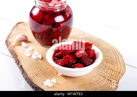 Eingelegte rote betroot in der Schüssel und Glas auf Holz- Hintergrund. Stockfoto